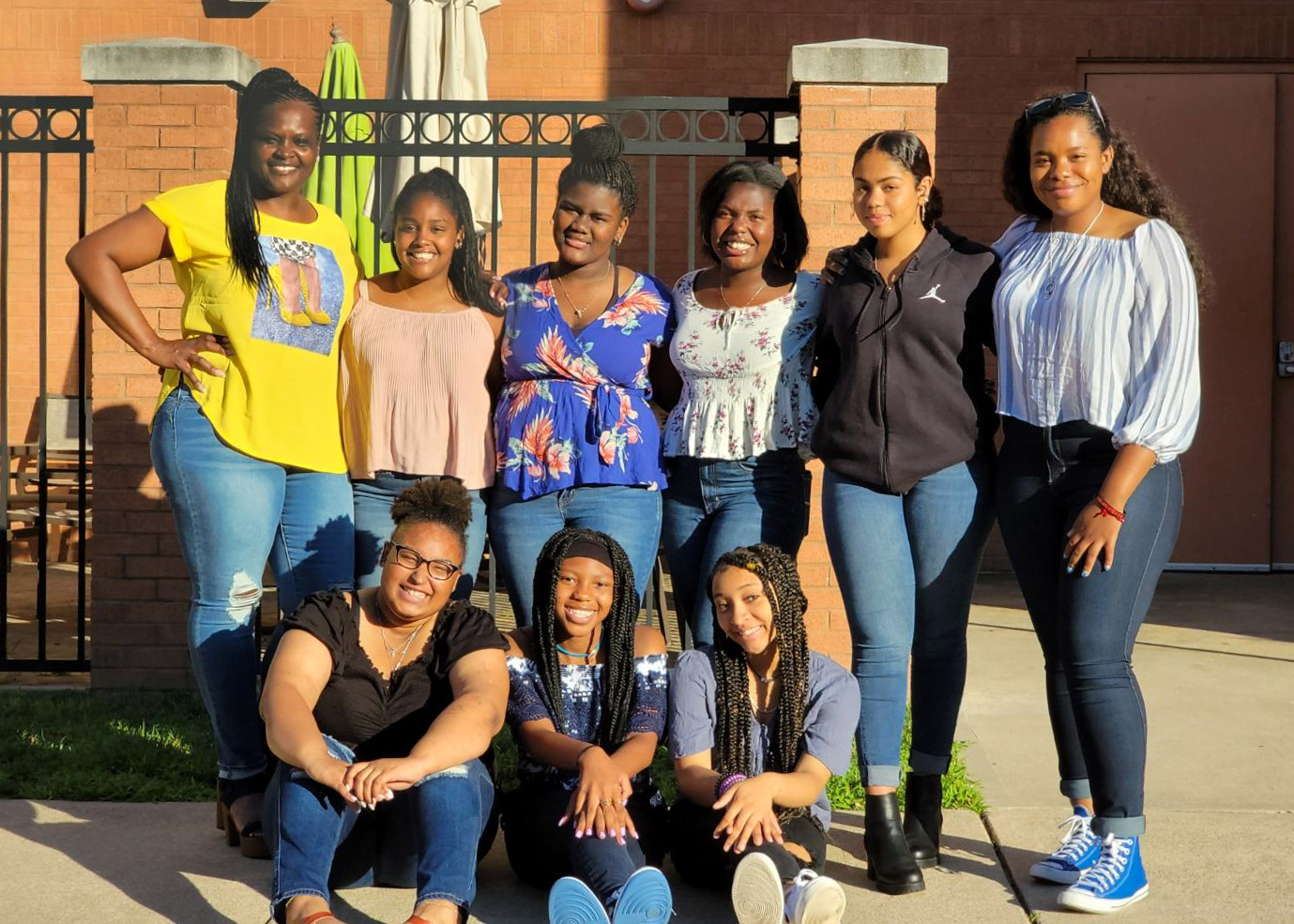 A group of 9 teenage girls post for a photo during a shopping trip.