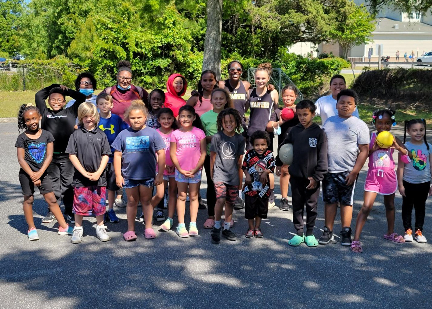 A large group of young children pose for a photo in the backyard of the youth center.