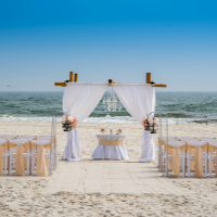 Image of a wedding arbor, aisle and chairs set up on the beach.