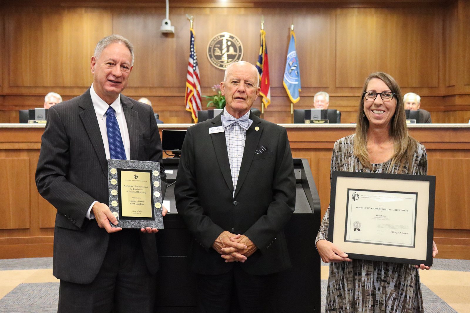 Dare County Board of Commissioners Chairman Bob Woodard stands with Finance Director David Clawson and Assistant Finance Director Sally DeFosse, each holding their awards.