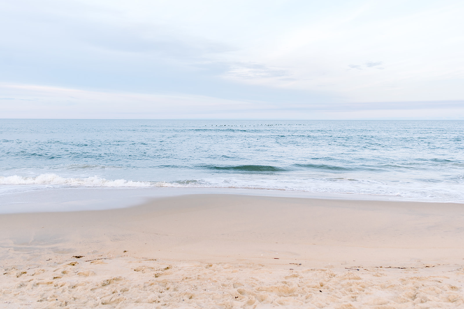 Image of waves softly washing along a beach at sunrise.