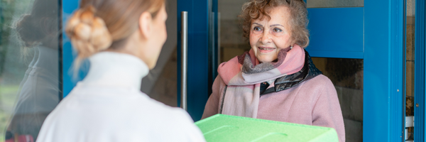 Image of a woman delivering a meal to an elderly woman.