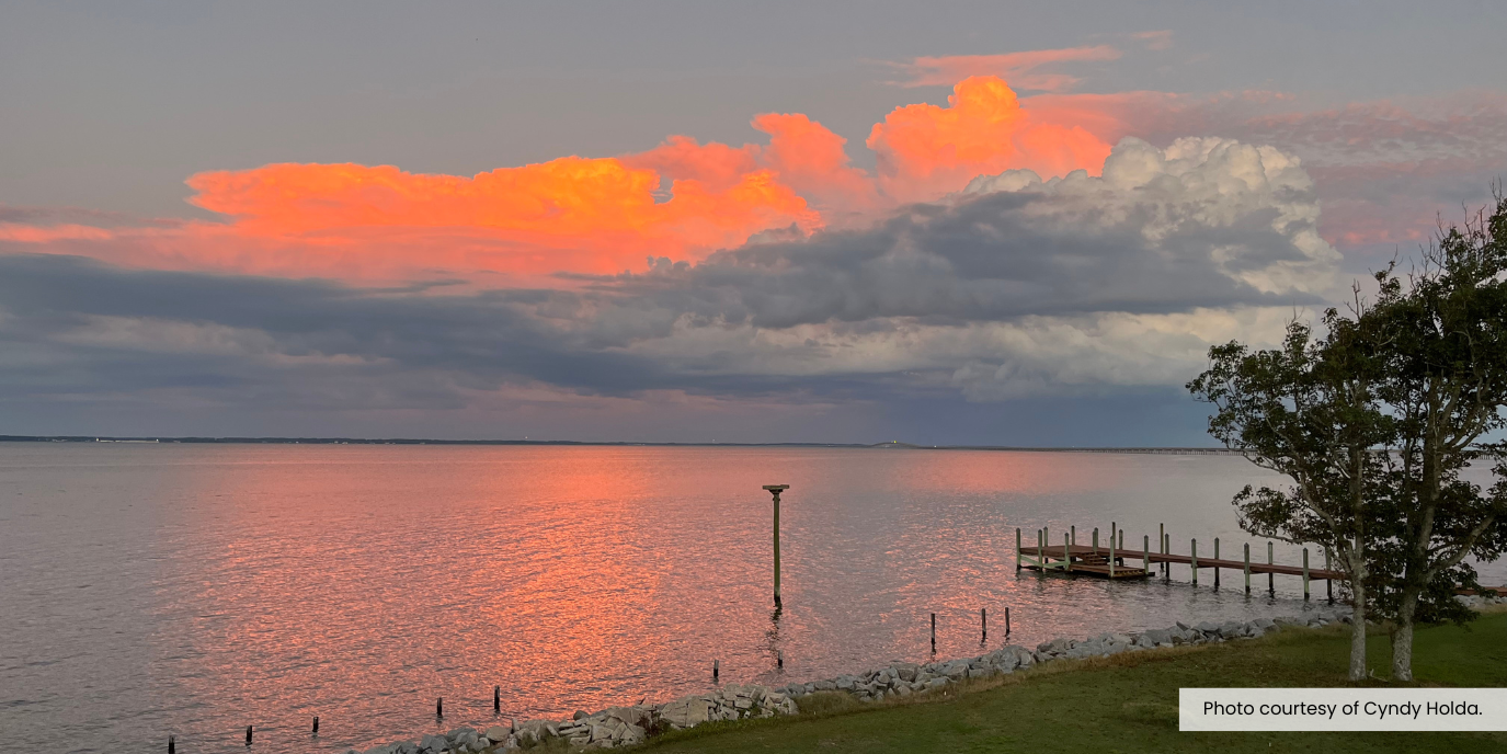 Image of a cloudy orange sunset over a body of water in Manns Harbor.