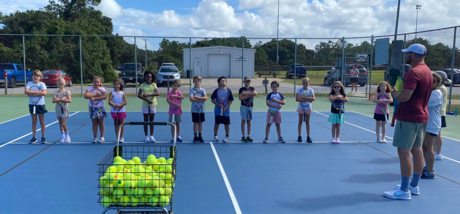 Group of OBXTA Try Tennis Youth players lined up on a tennis court.