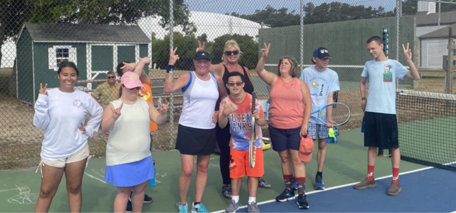 OBXTA volunteers and Special Olympics athletes pose for a photo on the tennis courts.